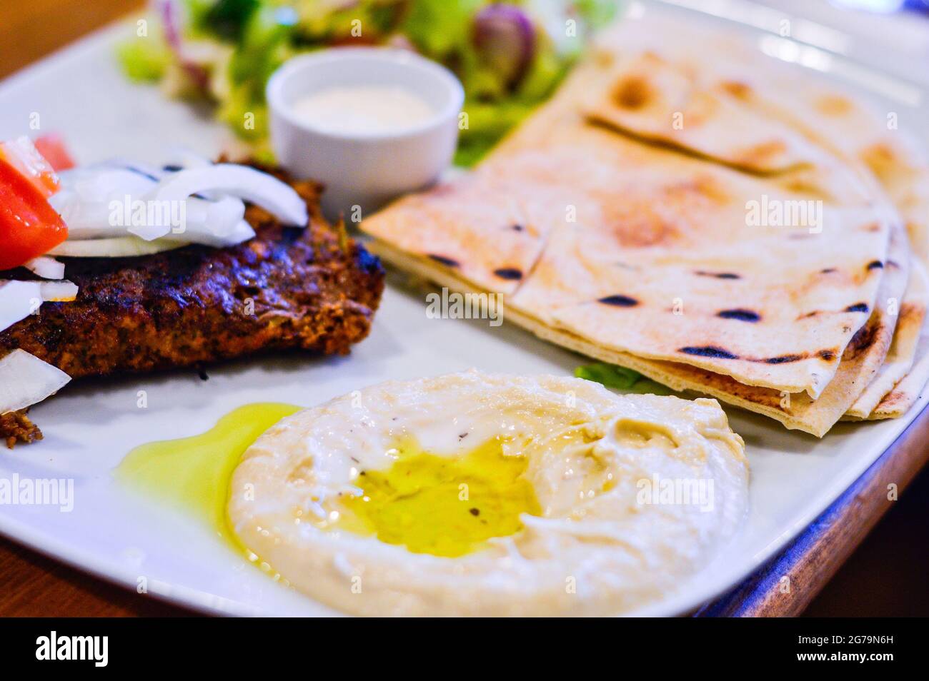 Agnello tritato alla griglia con Hummus, pane Pitta e insalata in piatto bianco. Autentica cucina mediorientale dal ristorante Foto Stock