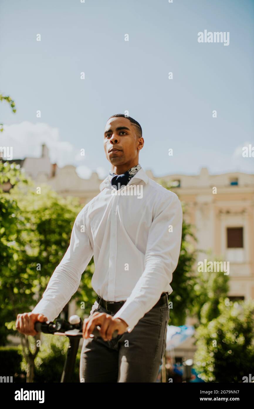 Bel giovane afroamericano con scooter elettrico su una strada Foto Stock