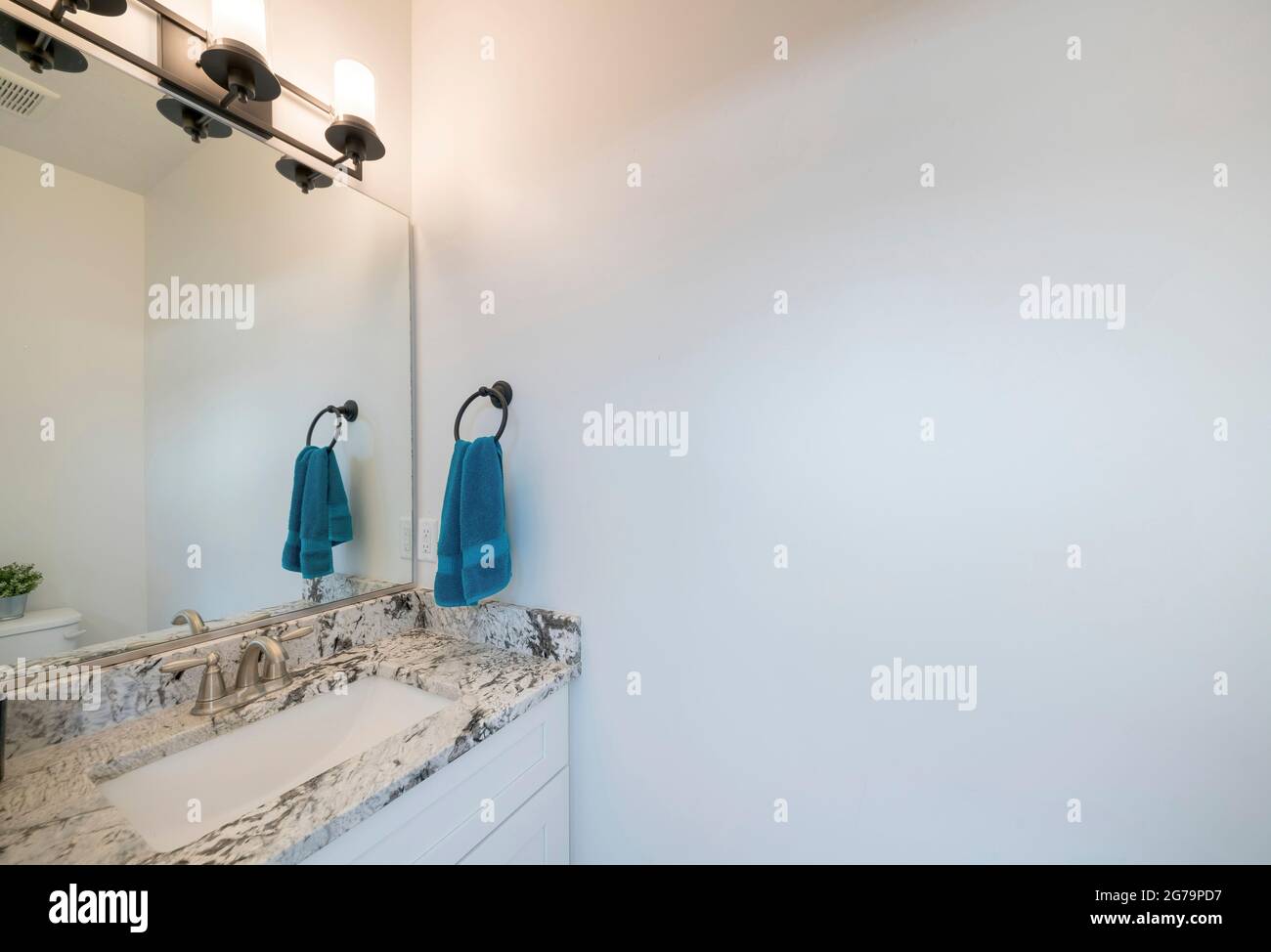 Lavandino di una stanza da bagno con piano in marmo e lampade in metallo nero Foto Stock
