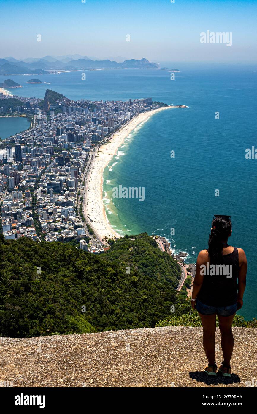 Una donna sulla cima della montagna guardando la vista panoramica di Ipanema / Leblon Beach e Lagoa Rodrigo de Freitas dalla cima del Dois Irmaos due fratelli montagna a Rio de Janeiro, Brasile Foto Stock