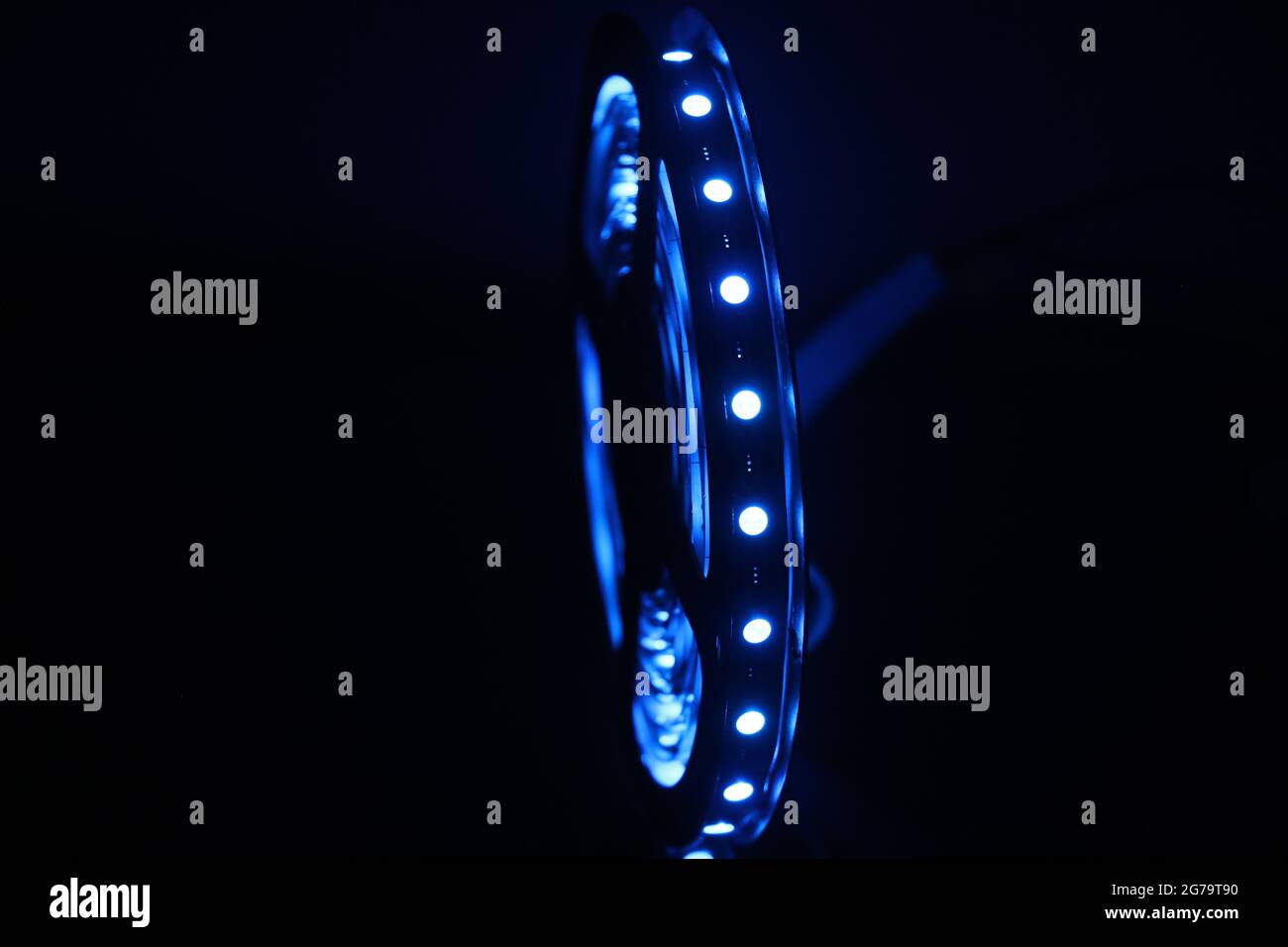 Striscia LED blu brillante isolata su sfondo scuro. Striscia verticale del rotolo di LED Foto Stock
