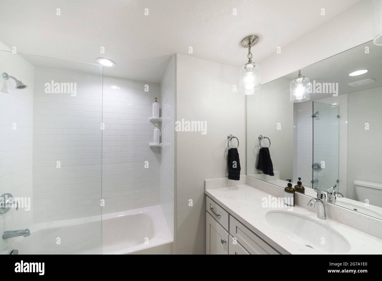 Piccolo e moderno bagno bianco con vasca da bagno alcova con parete  divisoria in vetro e piastrelle bianche Foto stock - Alamy