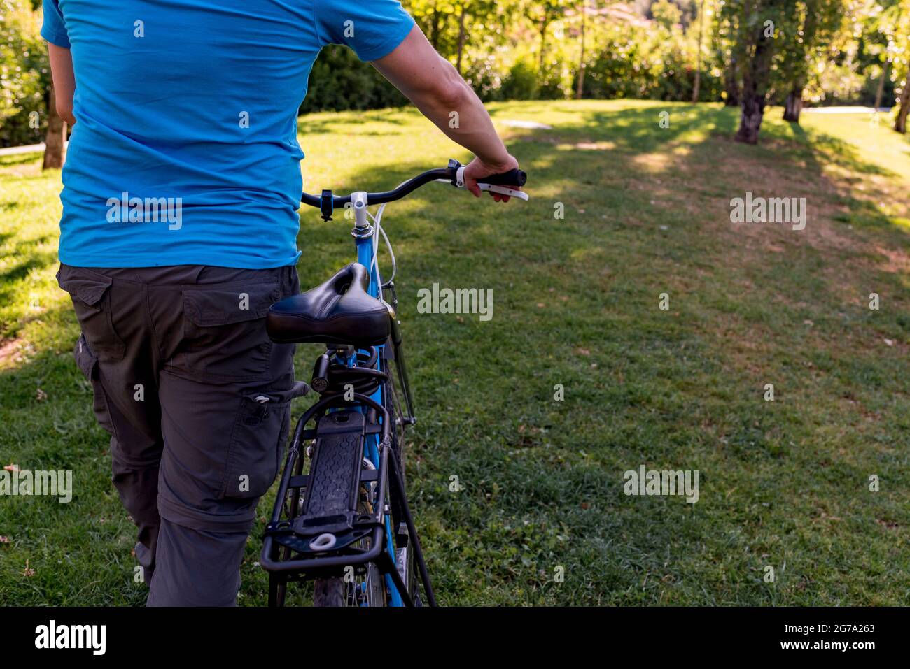 Uomo irriconoscibile che cammina nel parco con la sua bicicletta Foto Stock