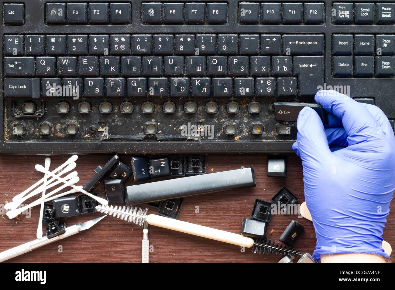 Un tecnico di elettronica professionale rimuove i tasti da una vecchia tastiera wireless del computer sporca. Gli attrezzi per la riparazione e la pulizia Foto Stock