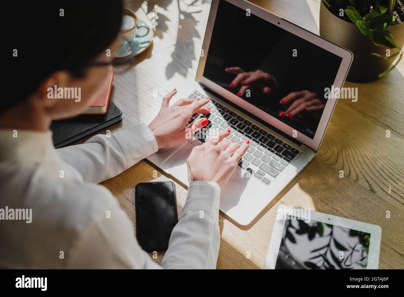 Vista posteriore di una donna d'affari che scrive sul computer portatile in ufficio. Foto Stock