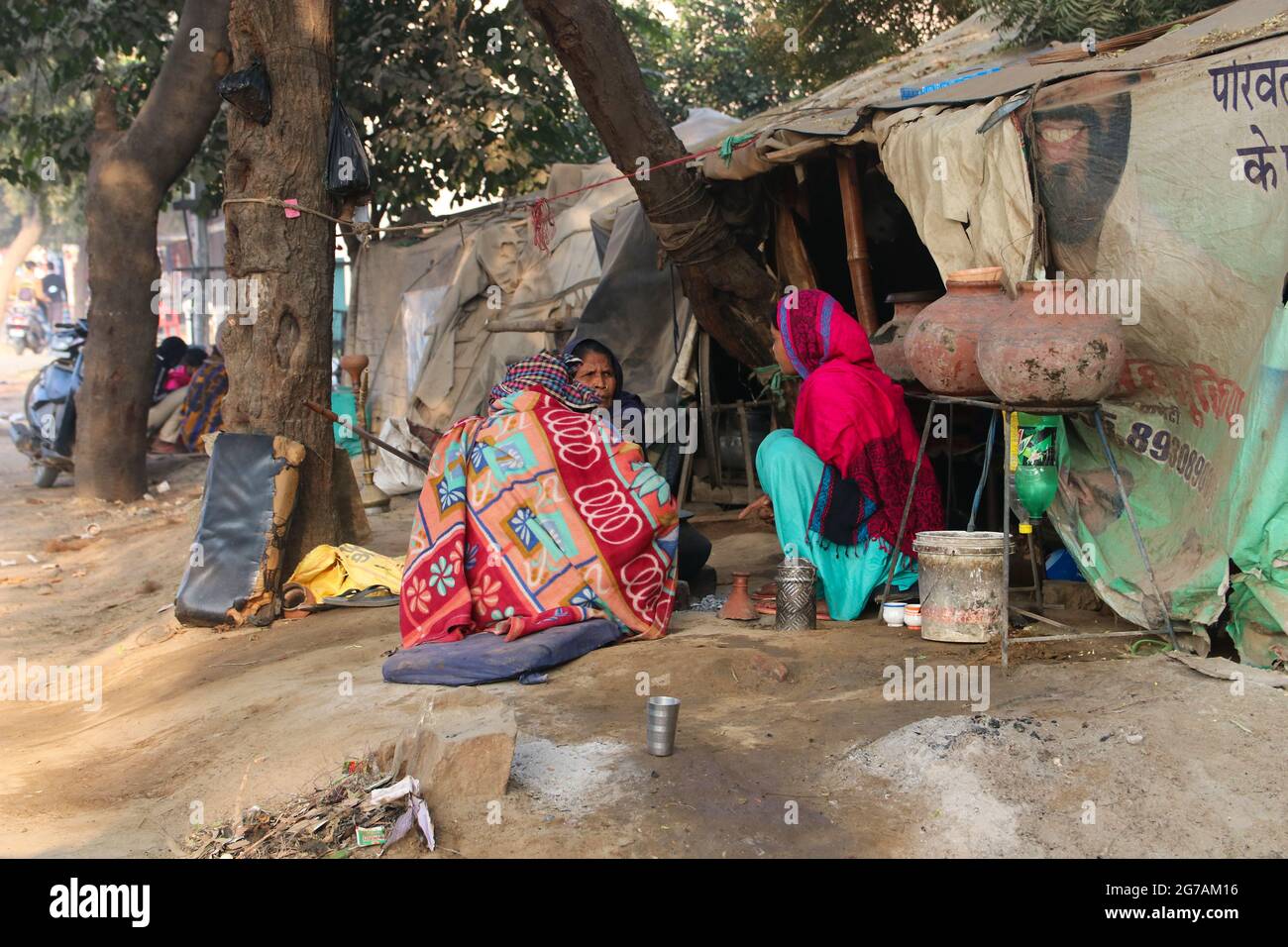 Indiani che non hanno la propria casa. La gente crogiolarsi alla luce del sole dopo una notte fredda. Foto Stock