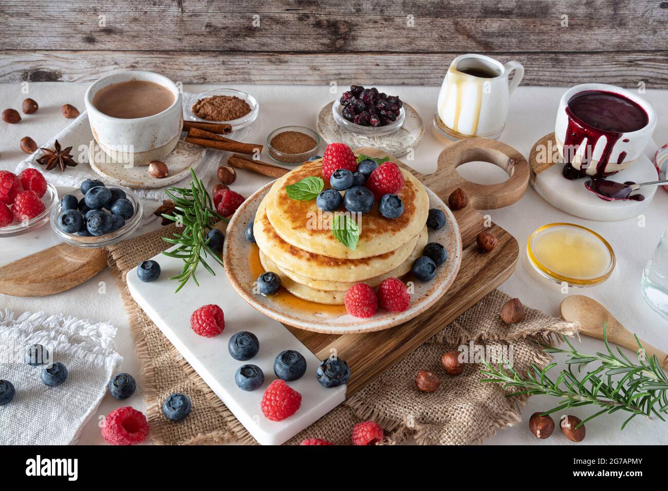 Frittelle con sciroppo d'acero, mirtilli e lamponi per colazione Foto Stock