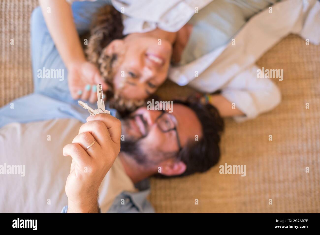 Felice giovane coppia mostra nuove chiavi della propria casa eccitata a muoversi insieme, sorridente amorevole marito adulto e moglie overjoyed i compratori di prima volta delocalizzare affitto appartamento condiviso Foto Stock