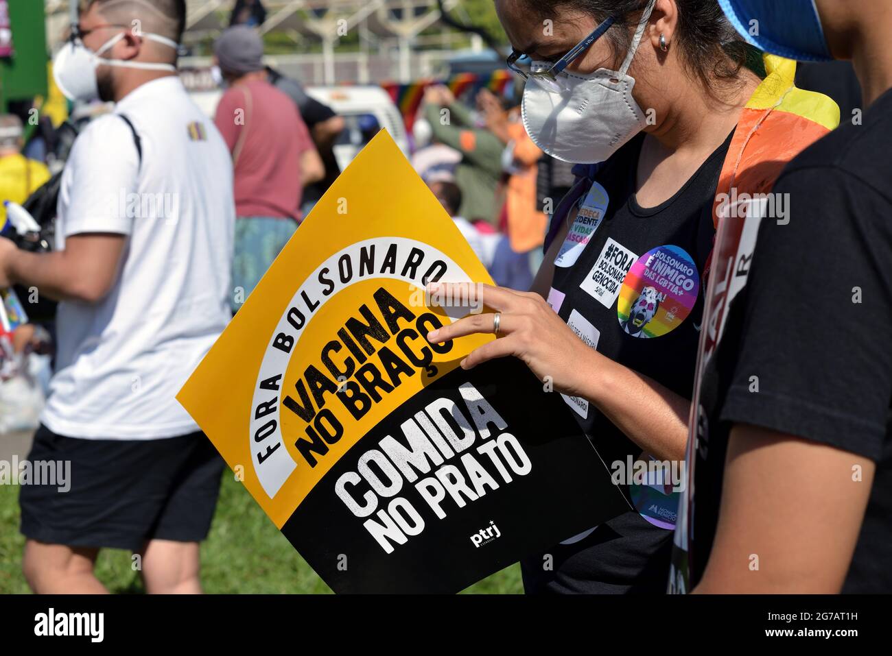 Brasile – Luglio 3,2021: Un marcher tiene un cartello che dice ‘vaccino in braccio, cibo in tavola, Bolsonaro fuori’ durante una protesta tenutasi nel centro di Rio de Janeiro Foto Stock
