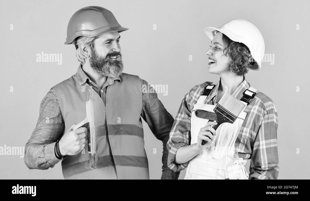 Nido di famiglia. Pittura pareti. Scegli il colore. Riparazione fai da te. Lavoratori edili. Ristrutturazione della casa. Casa in ristrutturazione per coppie allegre. Elmetto costruttore donna Foto Stock