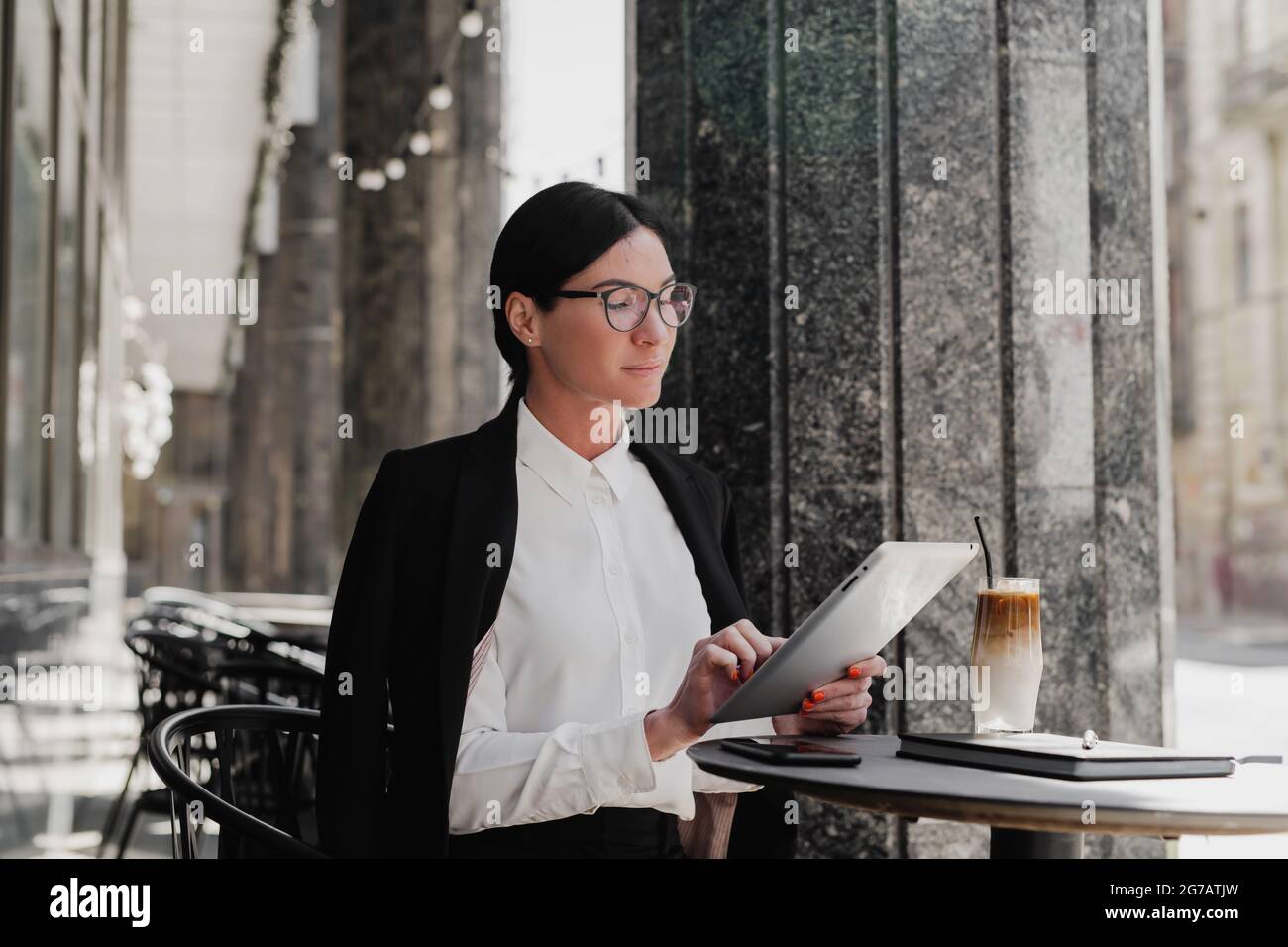 Elegante donna d'affari con computer tablet che beve caffè al bar. Foto Stock