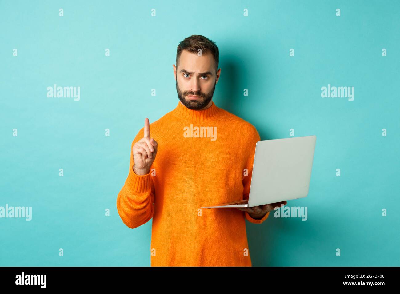 Immagine dell'uomo adulto che insegna online, mostrando il dito mentre si  usa il computer portatile, spiegando le regole, in piedi su sfondo azzurro  Foto stock - Alamy