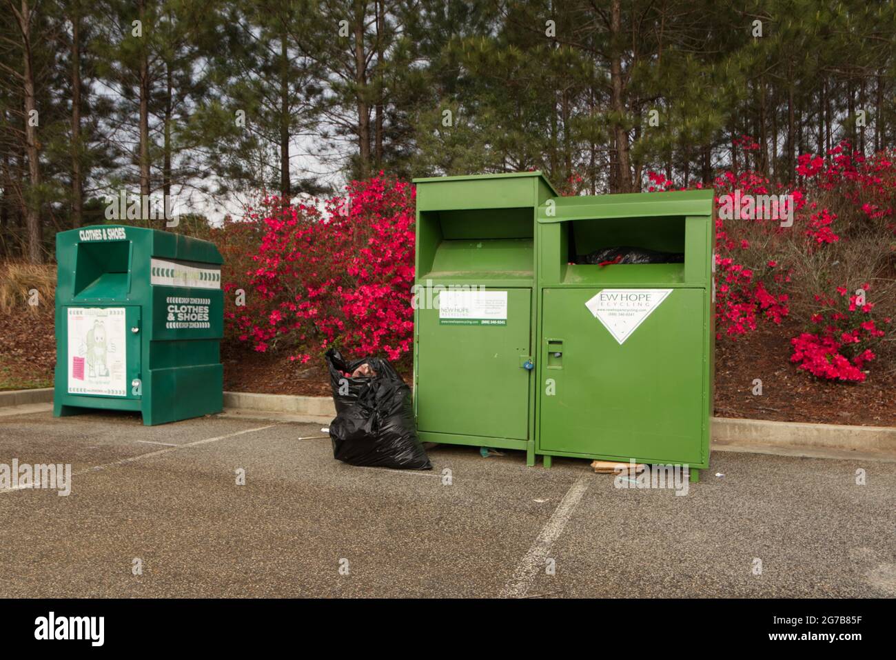 Augusta, GA USA - 04 10 21: Una fila di contenitori di raccolta per la raccolta delle donazioni e una borsa a terra con fiori rossi in fiore Foto Stock
