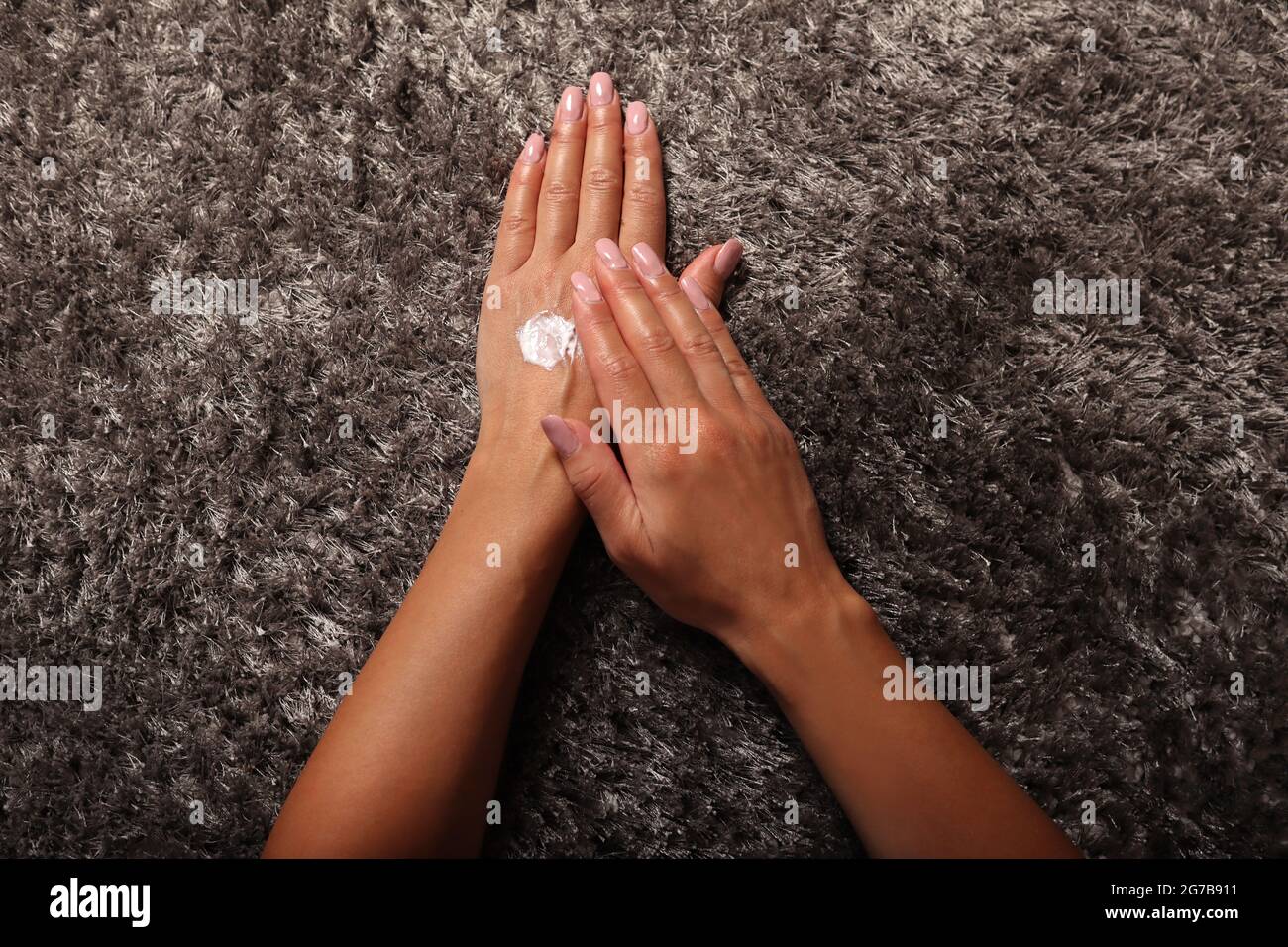 Donna che applica crema bianca a mano a casa. Concetto di bellezza e cura della pelle. Vista dall'alto, primo piano e spazio per la copia Foto Stock