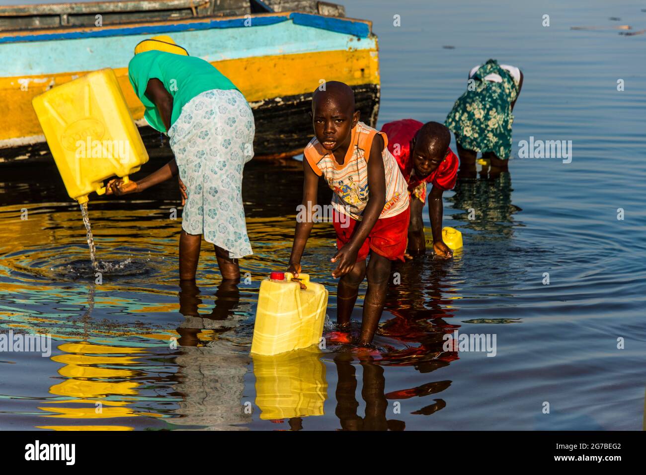 Bambini che riempiono l'acqua in barattoli sul lago Albert, Uganda, Africa Foto Stock