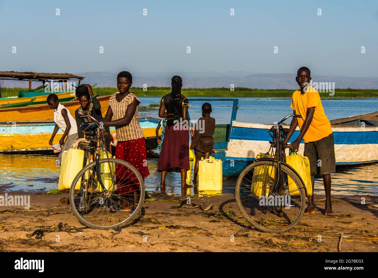 Bambini che riempiono l'acqua in barattoli sul lago Albert, Uganda, Africa Foto Stock