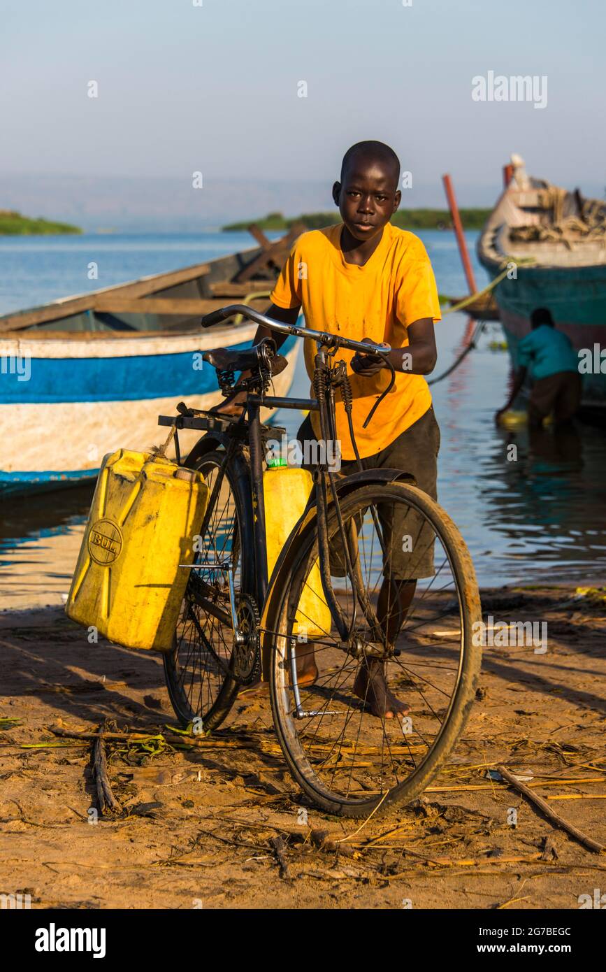Ragazzo che riempie l'acqua in barattoli al lago Albert, Uganda, Africa Foto Stock