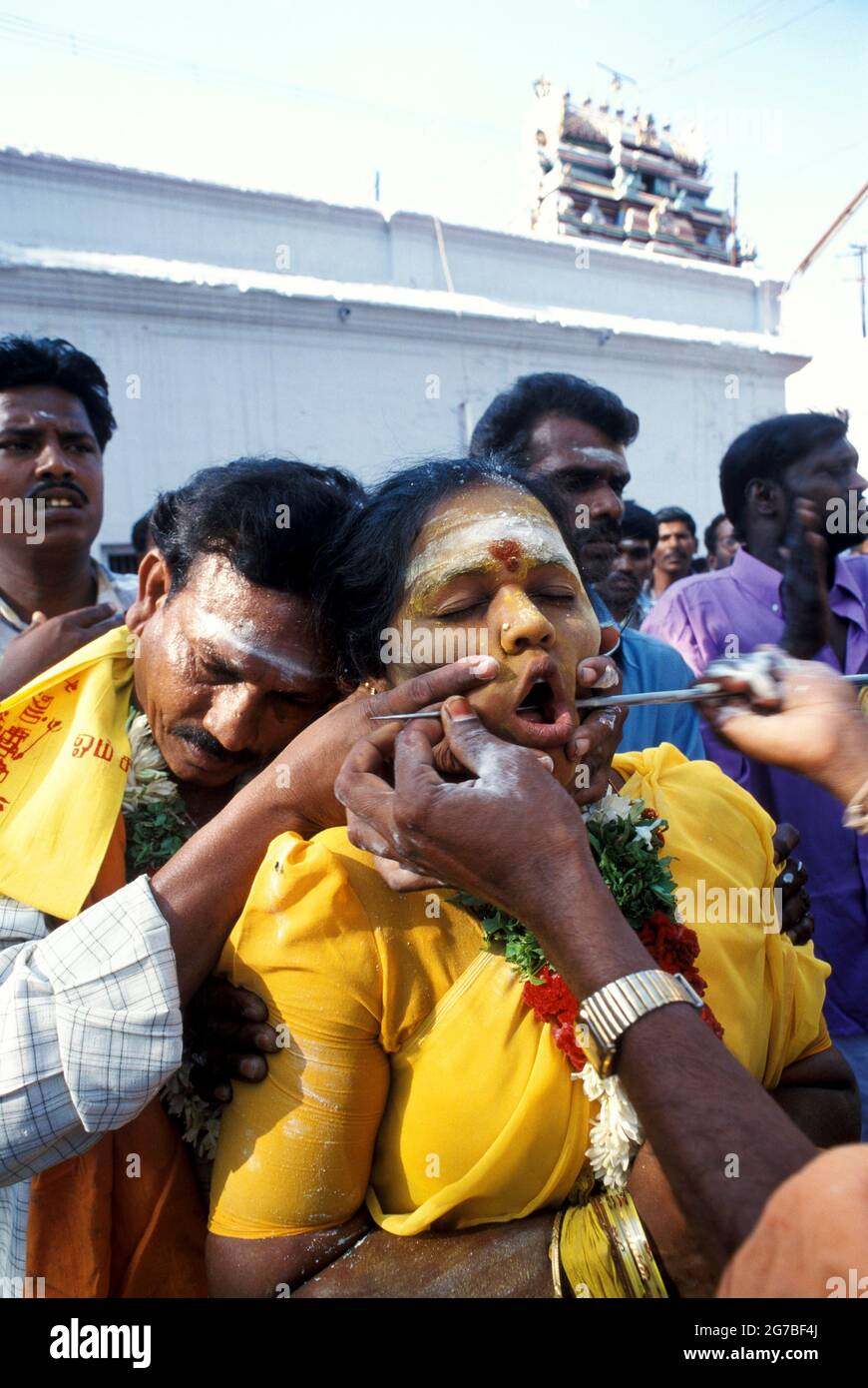 Il prete pierces un volto di womans con una lancia; asta di ferro. Mariamman festival a Coimbatore, Tamil Nadu, India Foto Stock