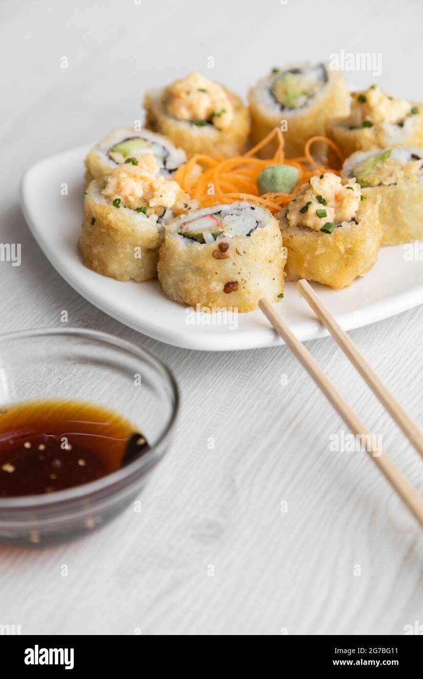 decorazione elegante e semplice di un piatto con panini di sushi, carote, bastoncini e contenitore con salsa di soia pronto per essere servito, cibo sano in studio, Foto Stock