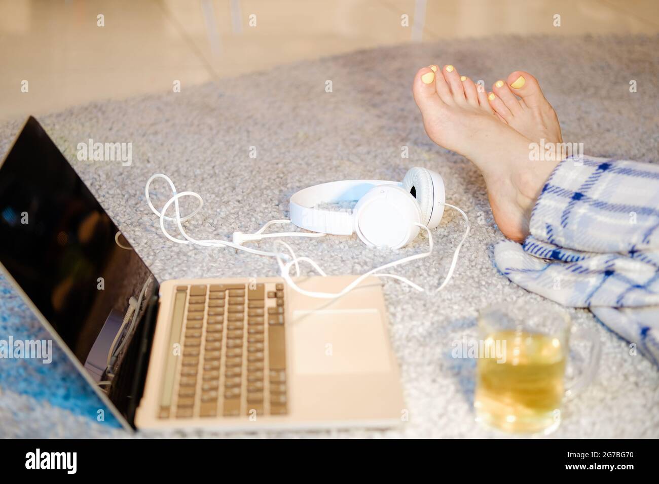 Gambe femminili con manicure giallo accanto al laptop, lavoro lontano o e-learning.Working da casa. Foto Stock