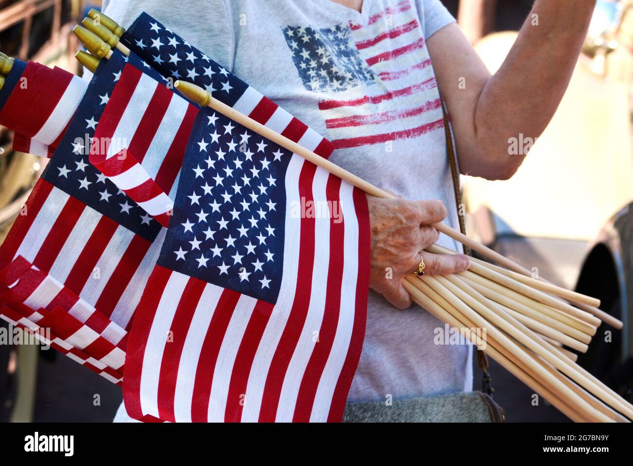 Una donna consegna piccole bandiere americane ad una mostra di automobili del 4 luglio a Santa Fe, New Mexico. Foto Stock