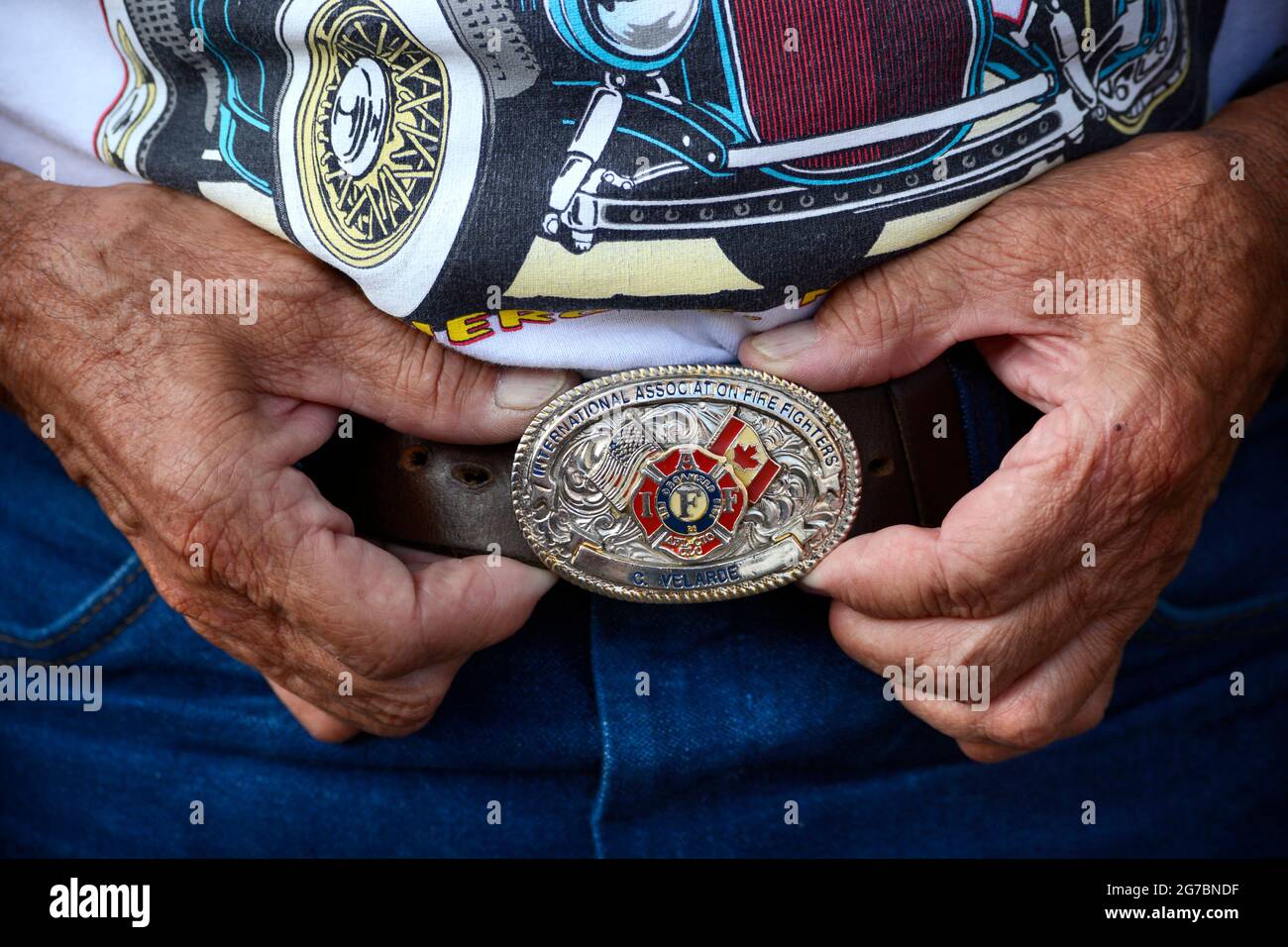 Un uomo mostra la sua fibbia della cintura della International Association of Firefighters in una mostra di auto a Santa Fe, New Mexico. Foto Stock