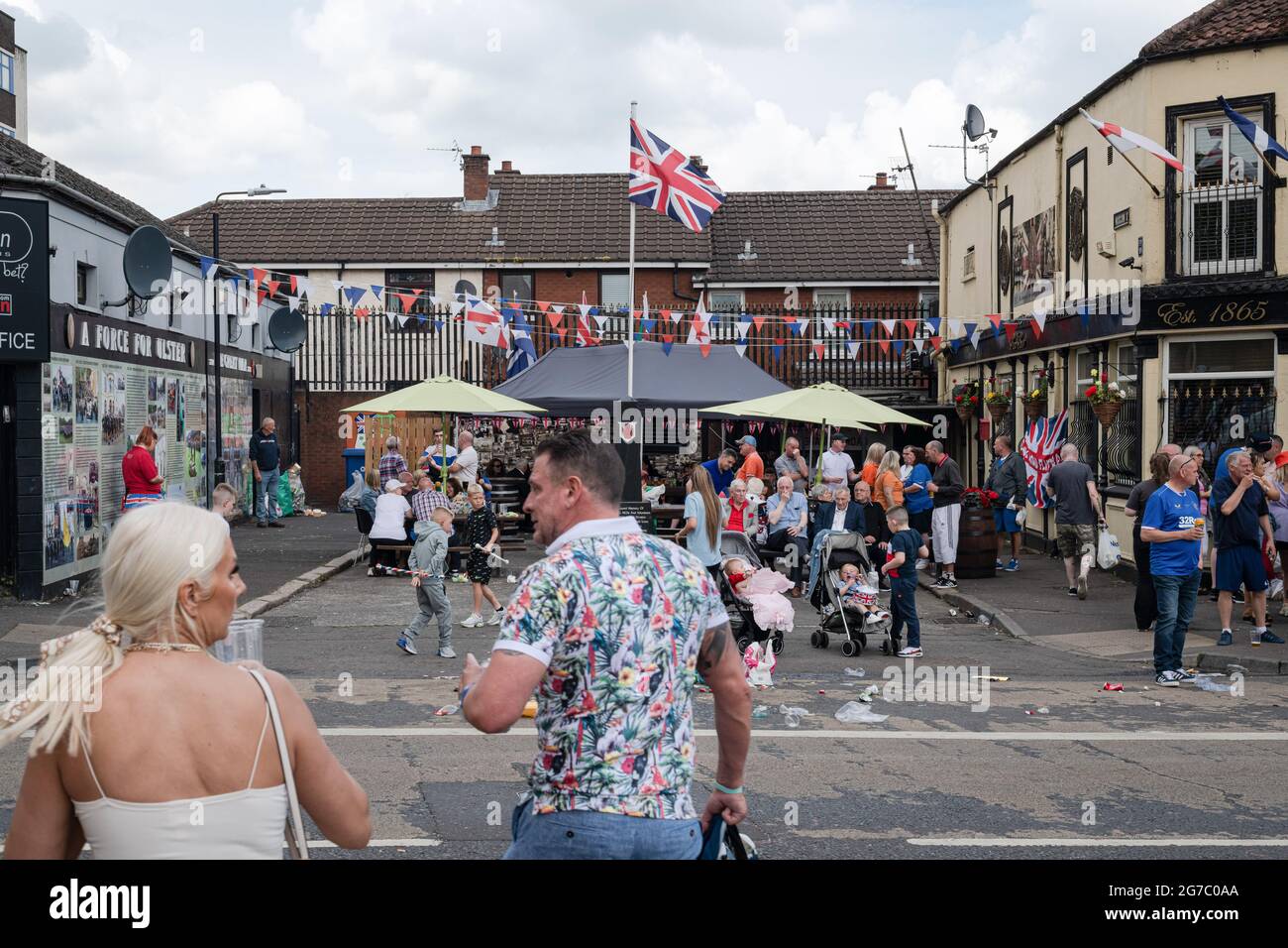Gli spettatori si riuniscono al REX Bar, una famigerata UVF (Ulster Volonteer Force) sulla Shankill Road per il 12 luglio Orange Order march. Il 12 luglio annuale delle parate dell'Ordine arancione si è svolto quest'anno dopo un periodo di pausa dovuto alla pandemia. Nonostante le speculazioni di un fine settimana potenzialmente riscaldato a causa dei protocolli Brexit e delle recenti tensioni correlate, nonché alcune contese il falò si accumula in tutto il Nord, le festività sono passate pacificamente. La stagione della parata segna l'anniversario della vittoria del re protestante Guglielmo d'Orange sulle forze cattoliche del re Giacomo nella Battaglia del ragazzo Foto Stock