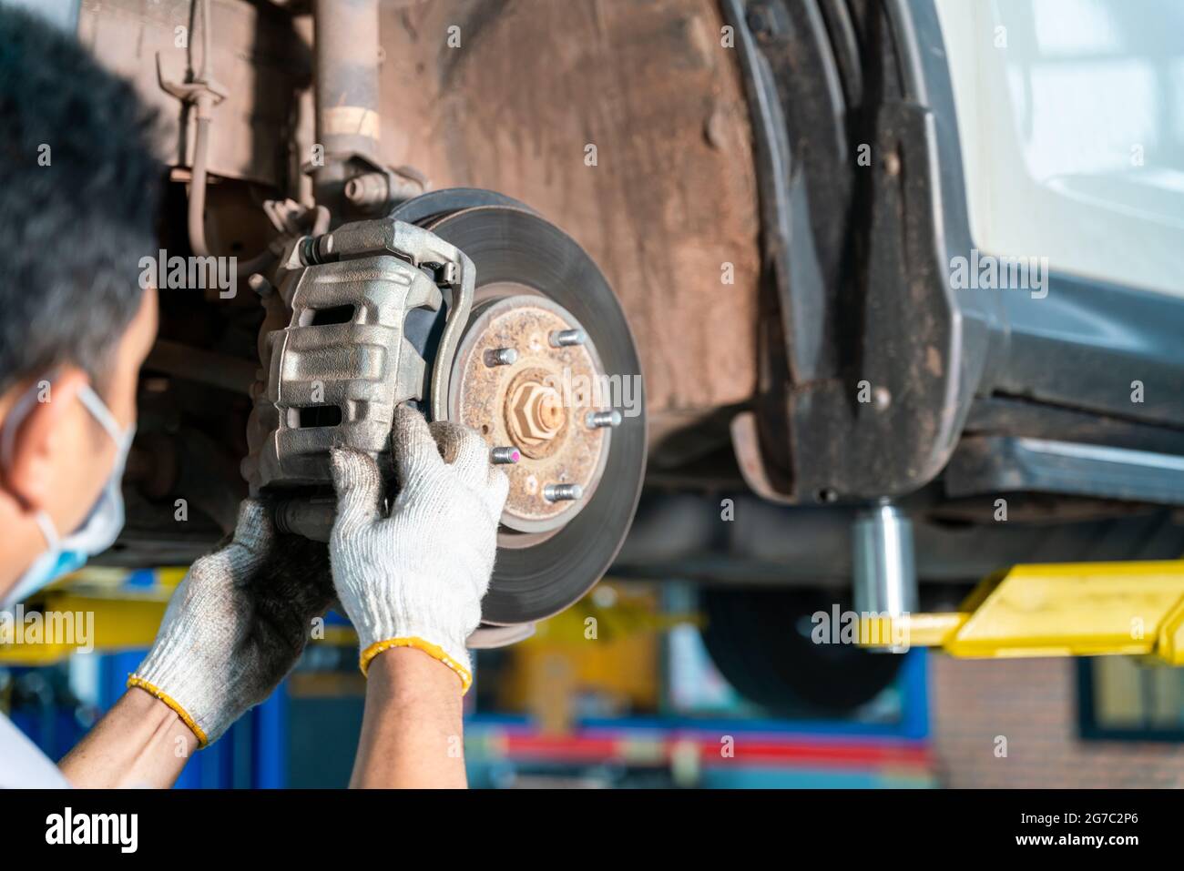 meccanico dell'automobile che esamina il disco del freno della ruota dell'automobile e le ganasce dell'automobile sollevata al centro di servizio di riparazione dell'automobile Foto Stock