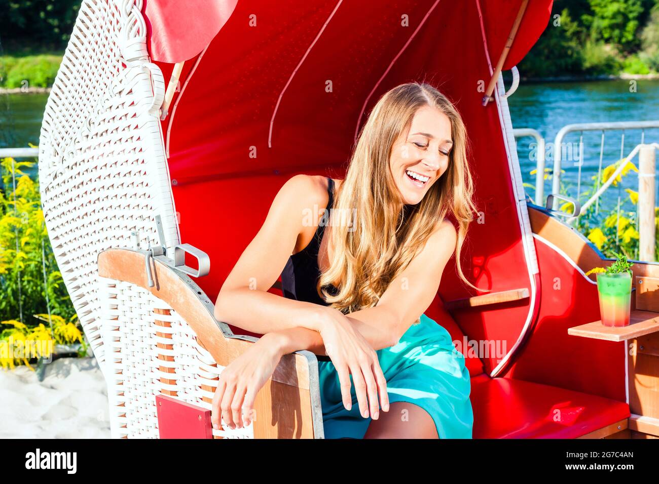 Giovane donna rilassante in vimini sedia al banco del bar in spiaggia Foto Stock
