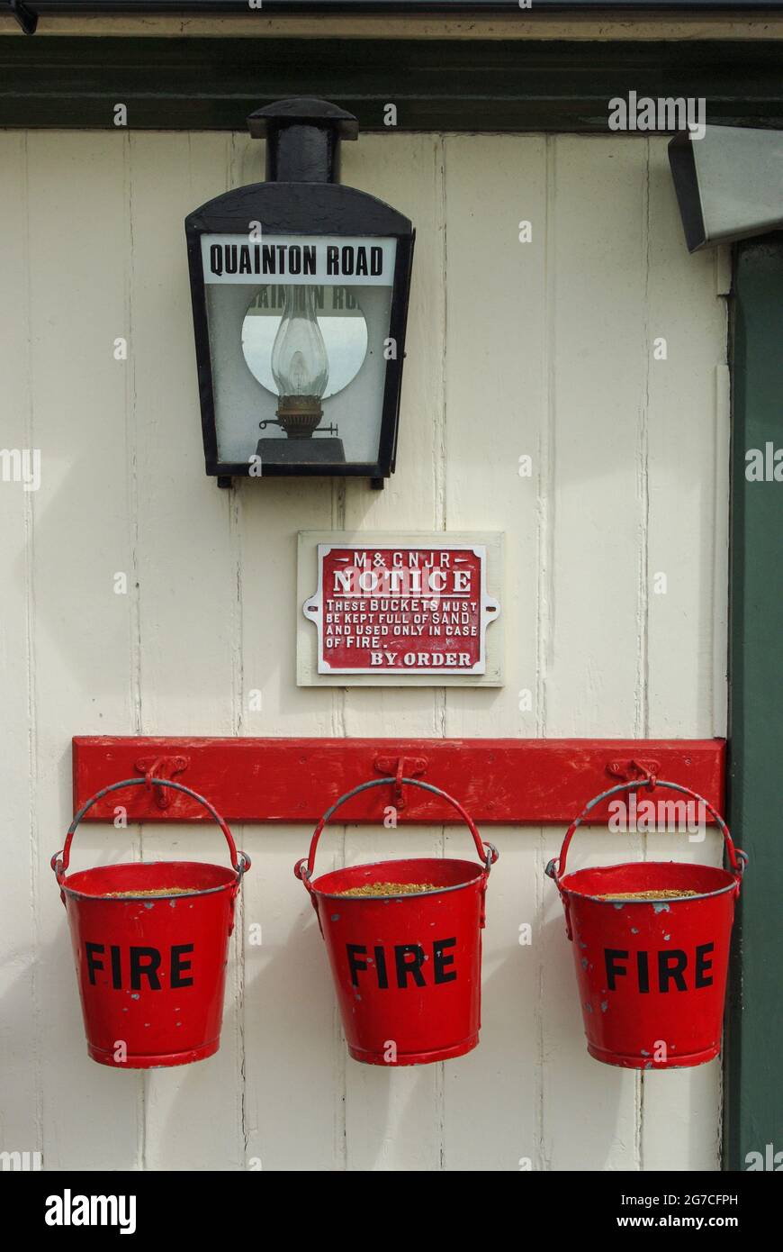Buckinghamshire, Centro ferroviario, Quainton, Regno Unito; benne antincendio, lampada e cartello sulla piattaforma della stazione Foto Stock
