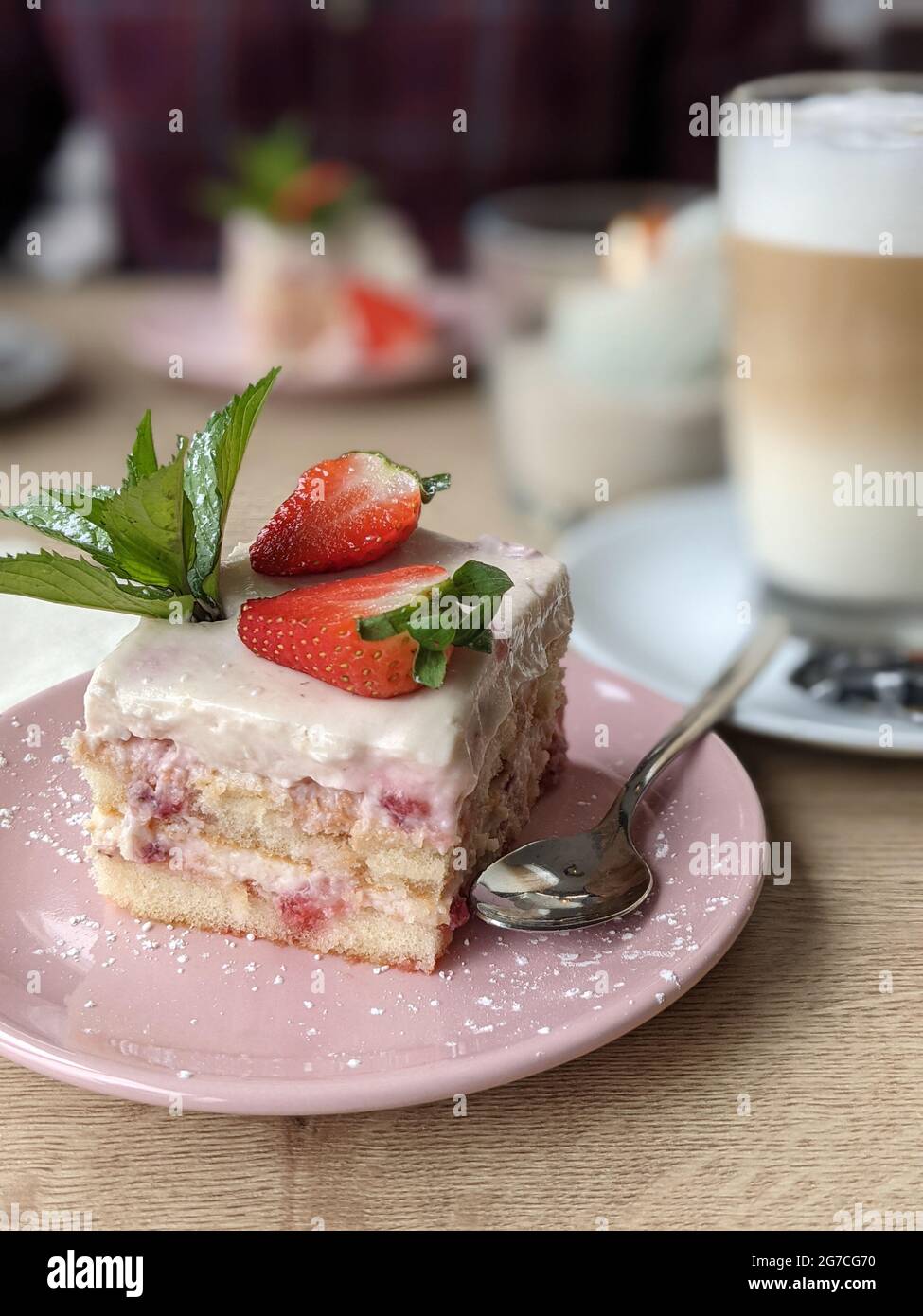 Primo piano di Tiramisu con fragola e un bicchiere di latte macchiato. Nahaufnahme eines Erdbeer Tiramisu und ein Glas latte macchiato. Foto Stock