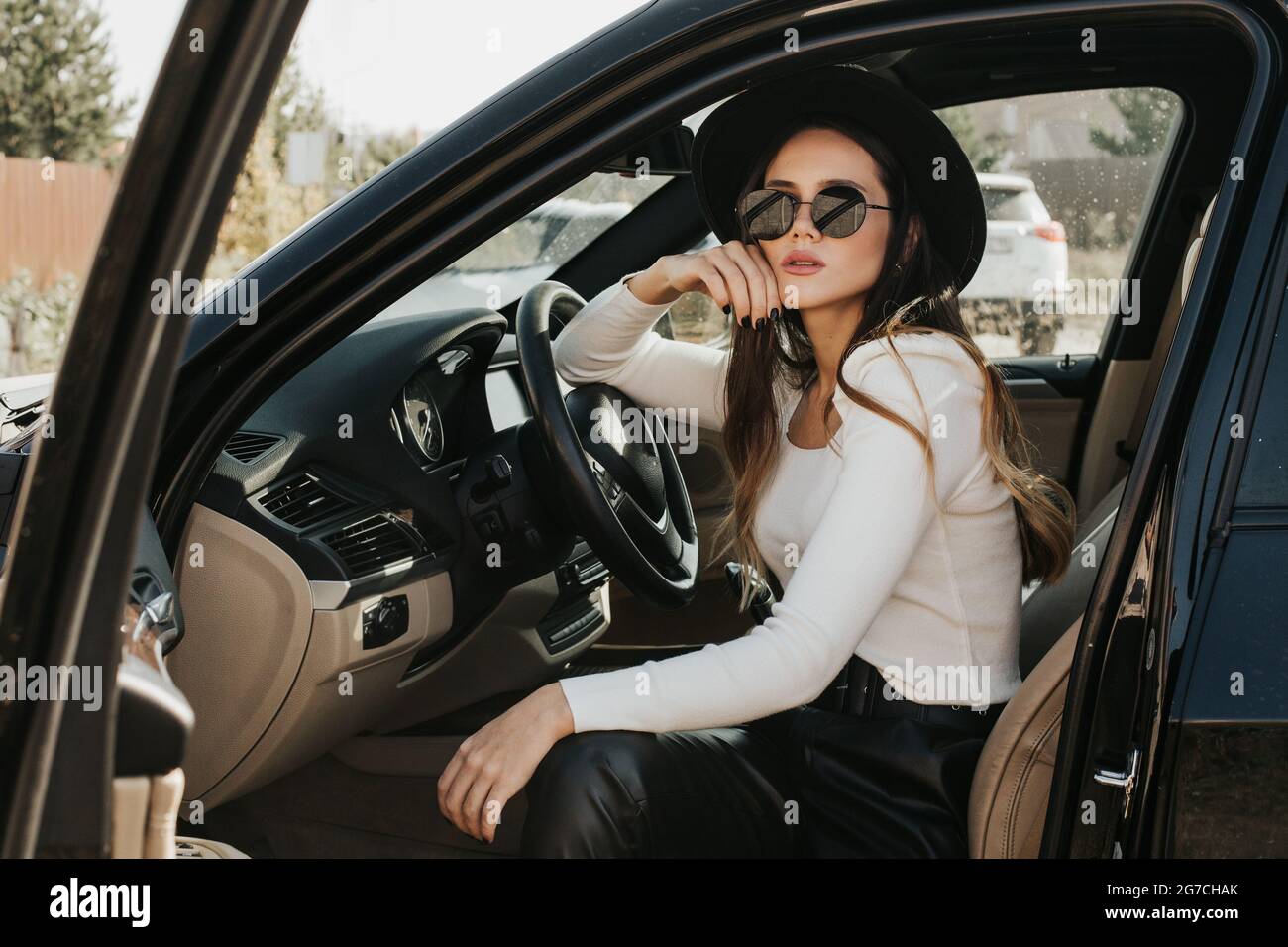 Ritratto di una bella giovane donna che guida una macchina. Donna in  occhiali oscuranti in posa in auto Foto stock - Alamy