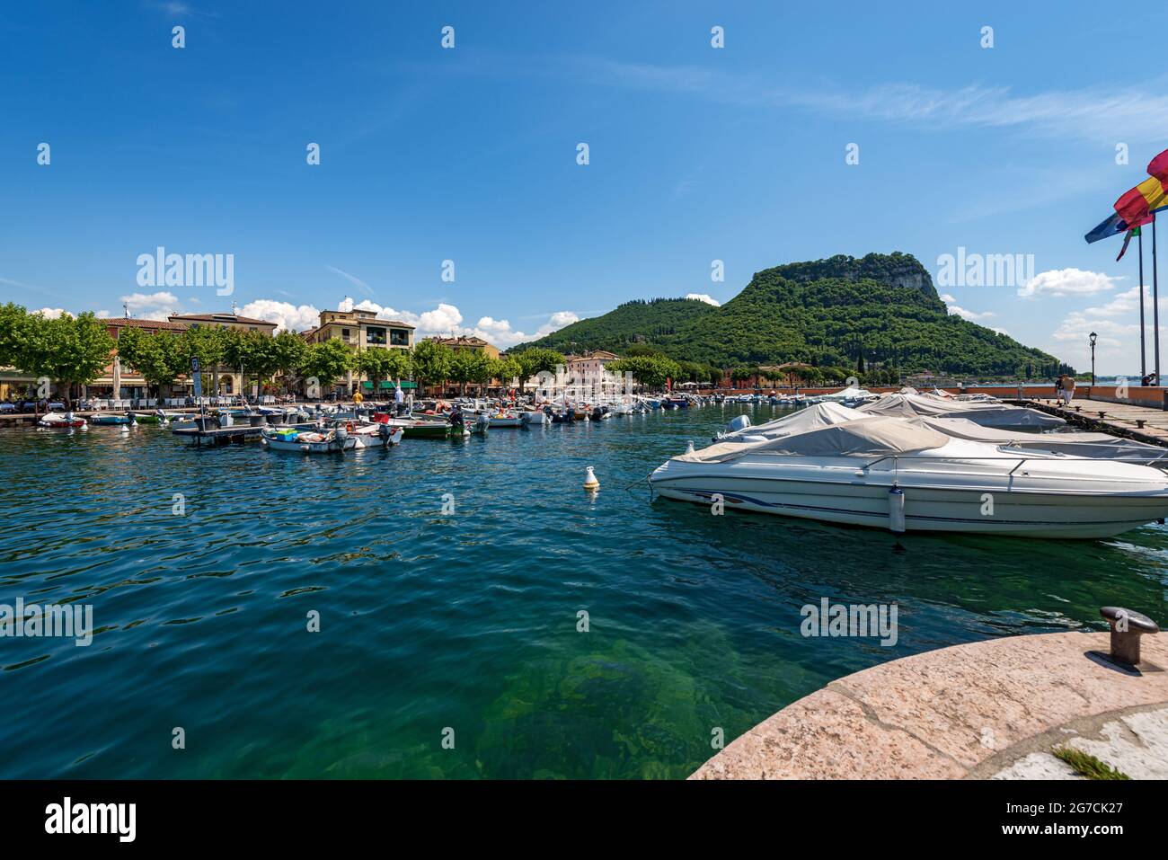 Piccolo porto con molte barche della città di Garda, località turistica sulla costa del Lago di Garda. Collina chiamata Rocca di Garda. Verona, Veneto, Italia, Europa. Foto Stock