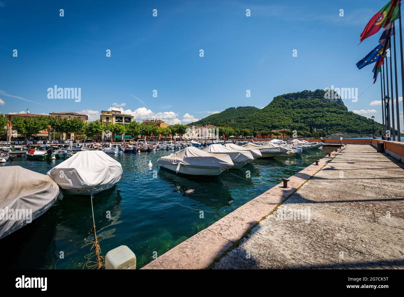 Porto della cittadina di Garda, località turistica sulla costa del Lago di Garda. All'orizzonte la collina chiamata Rocca di Garda. Verona, Veneto, Italia. Foto Stock
