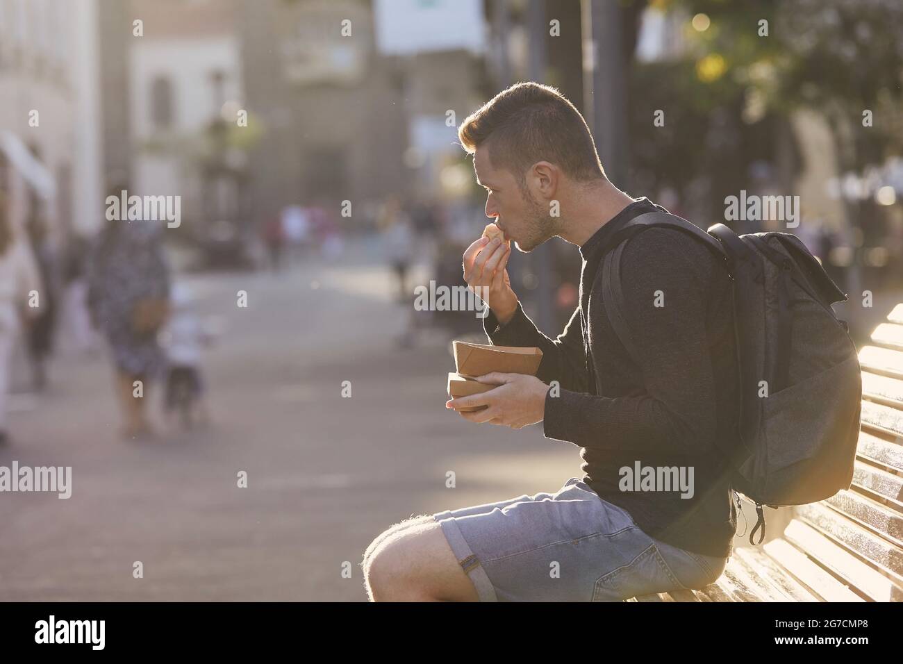 Uomo con zaino che mangia cibo di strada nella città storica. Turismo nel centro storico di San Cristobal de la Laguna inTenerife, Spagna. Foto Stock