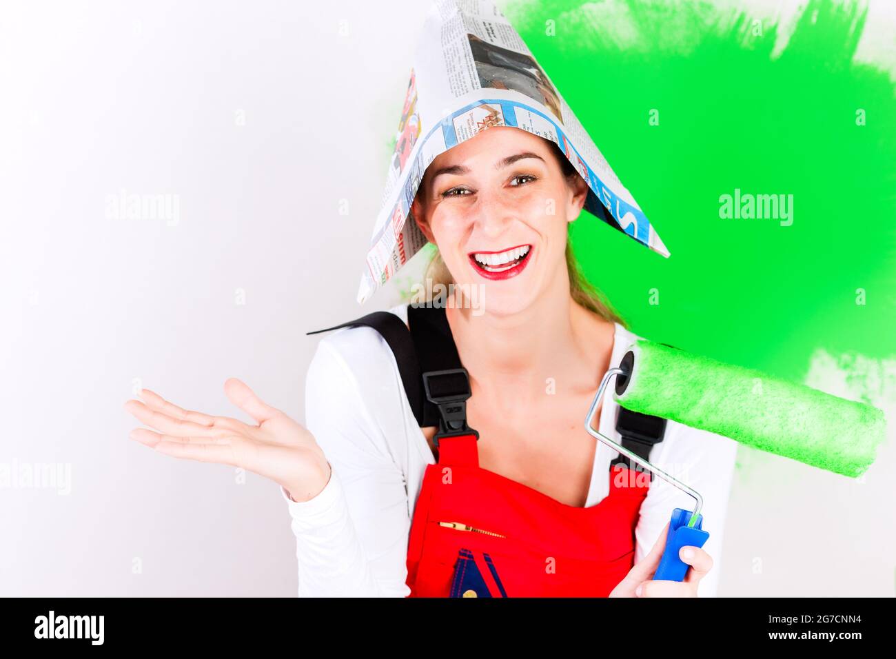 Donna con il divertimento a casa miglioramento muro dipinto con colore verde e spazzola Foto Stock
