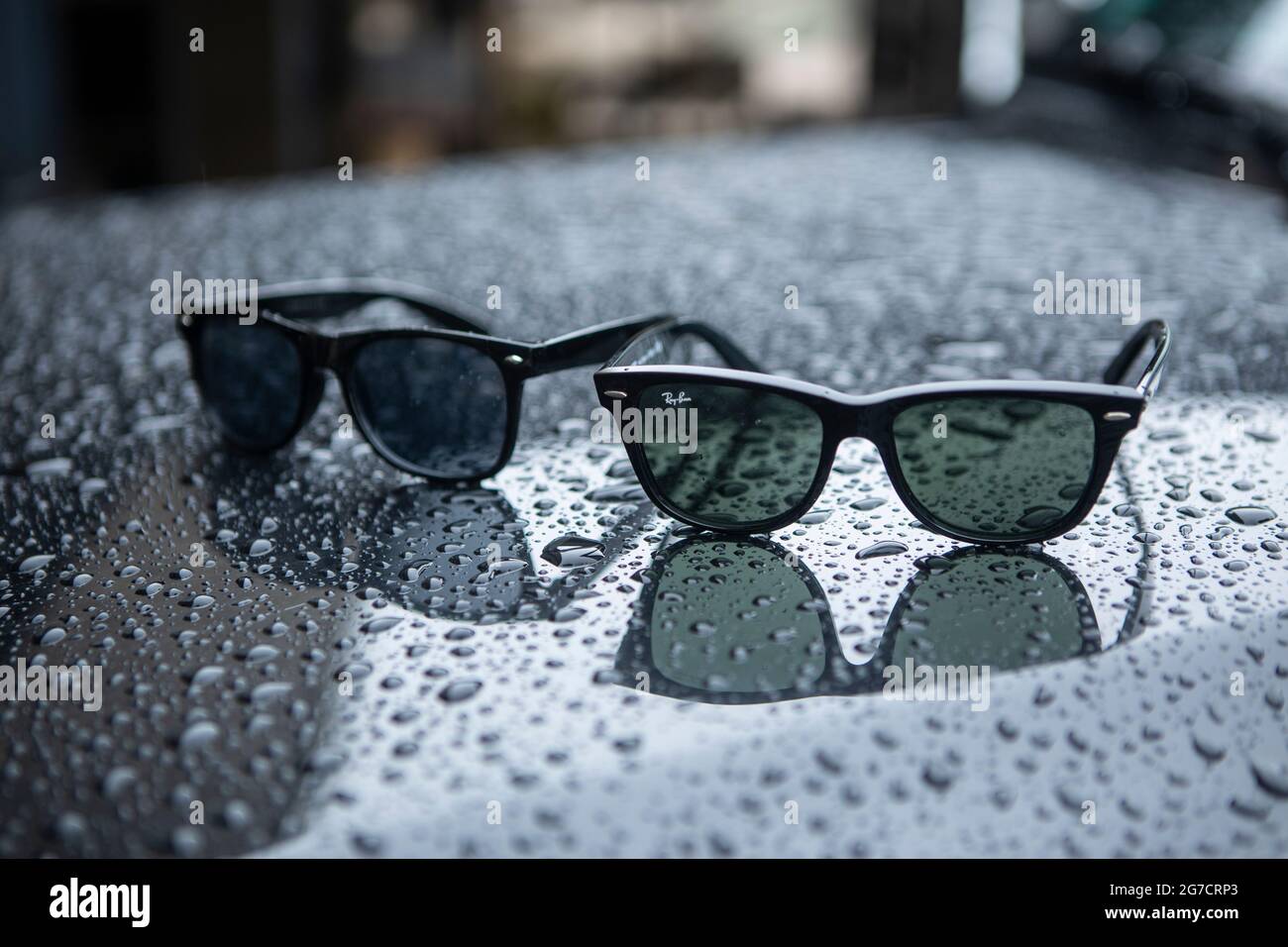 Ray Ban Wayfarer Sonnenbrille mit Regentropfen. Symboldbild Wetter, Sommer, Regenwetter, Regen. Daneben eine biliardo Fälschung oder Kopie. Foto Stock