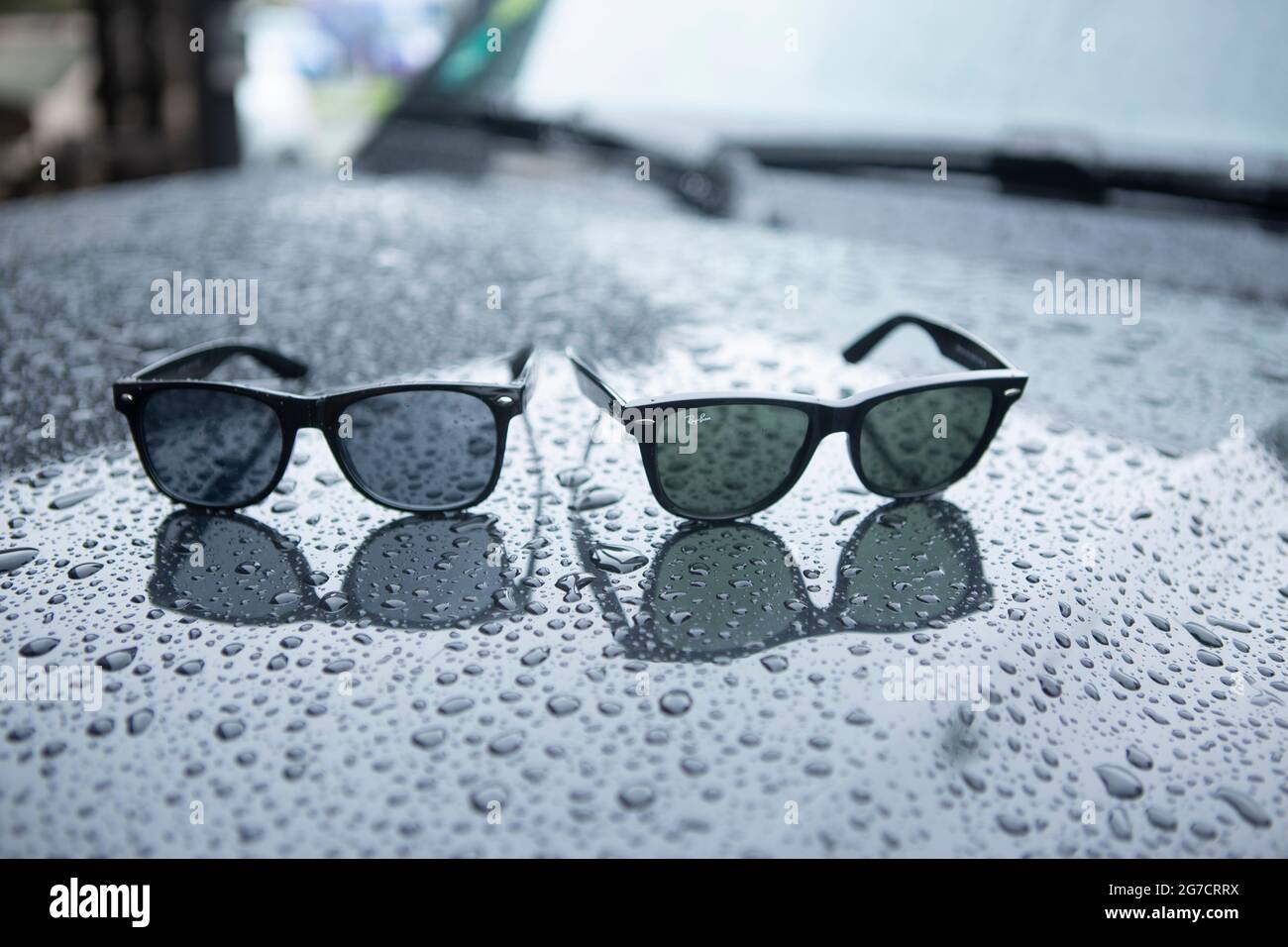 Ray Ban Wayfarer Sonnenbrille mit Regentropfen. Symboldbild Wetter, Sommer, Regenwetter, Regen. Daneben eine biliardo Fälschung oder Kopie. Foto Stock