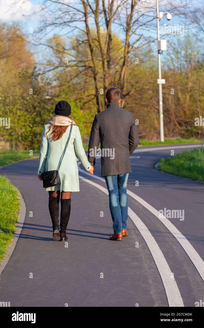 Un uomo e una donna stanno camminando di mano in mano sulla pista ciclabile. Poznan. Polonia. Foto Stock