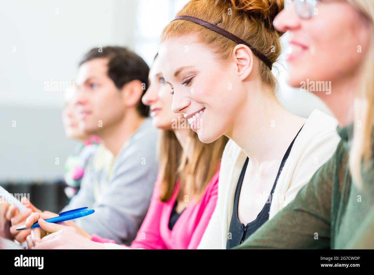 Studenti del college rendendo note di lezione in auditorium universitari Foto Stock