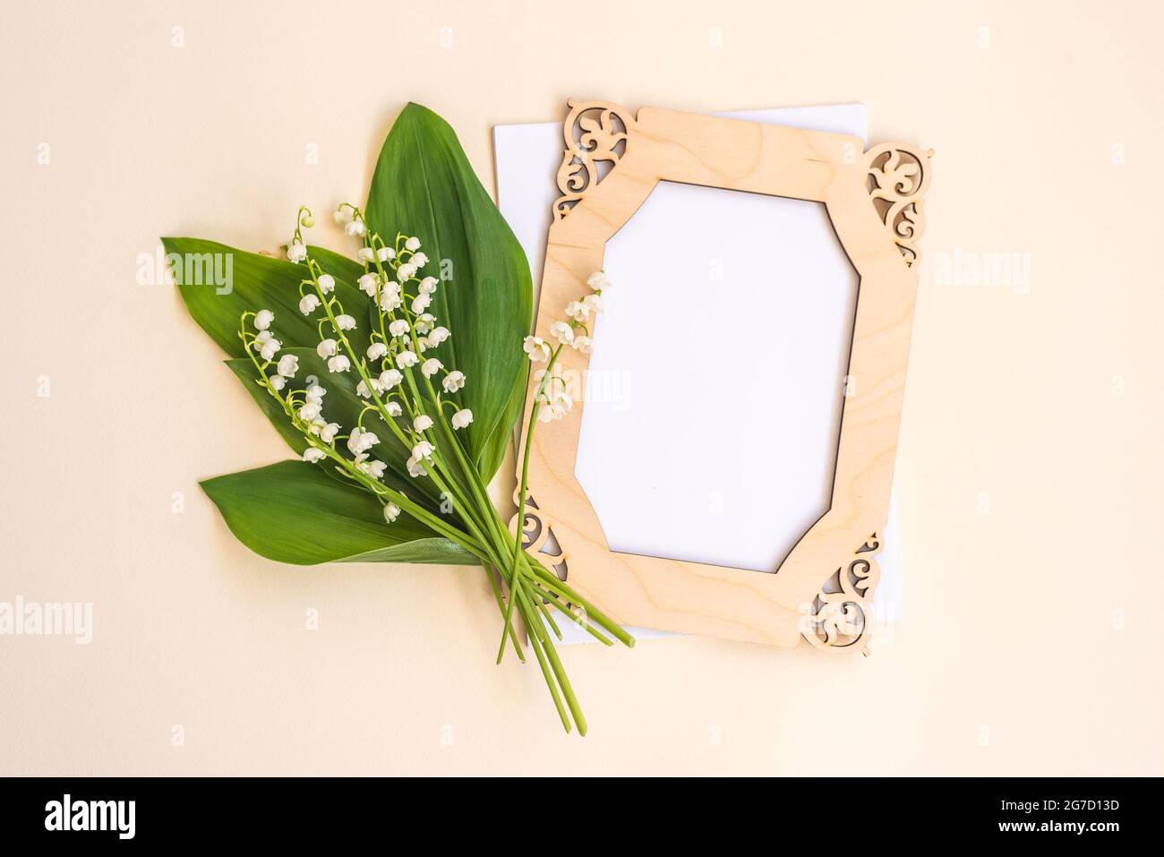 Gigli della valle bouquet cornice e carta bianca su beige Foto Stock