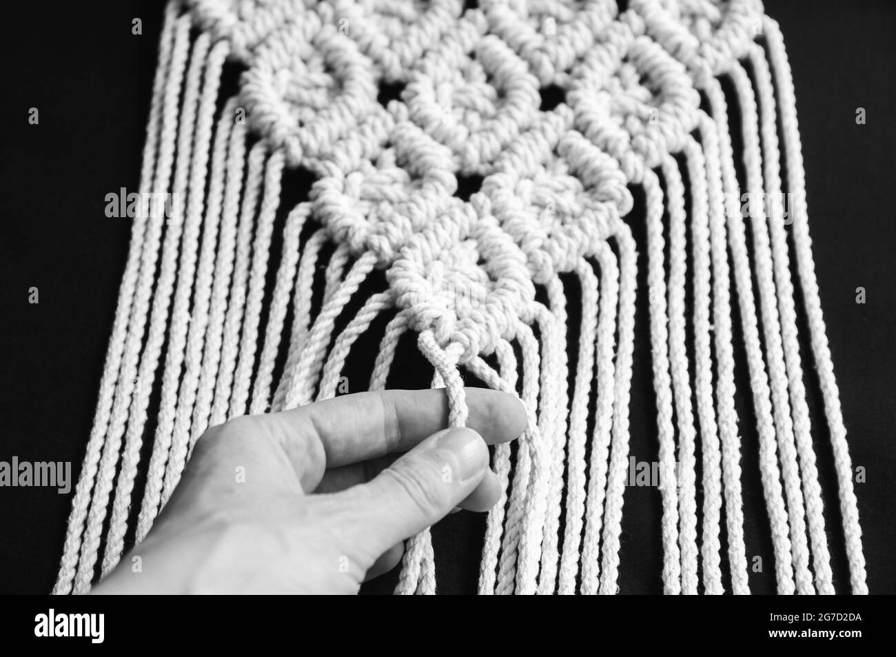 Decorativo artigianale elegante decorazione in macrame di cotone, interno hobby per appendere a parete. Arredamento per interni fai da te boho, maglieria moderna eco-friendly. Foto Stock