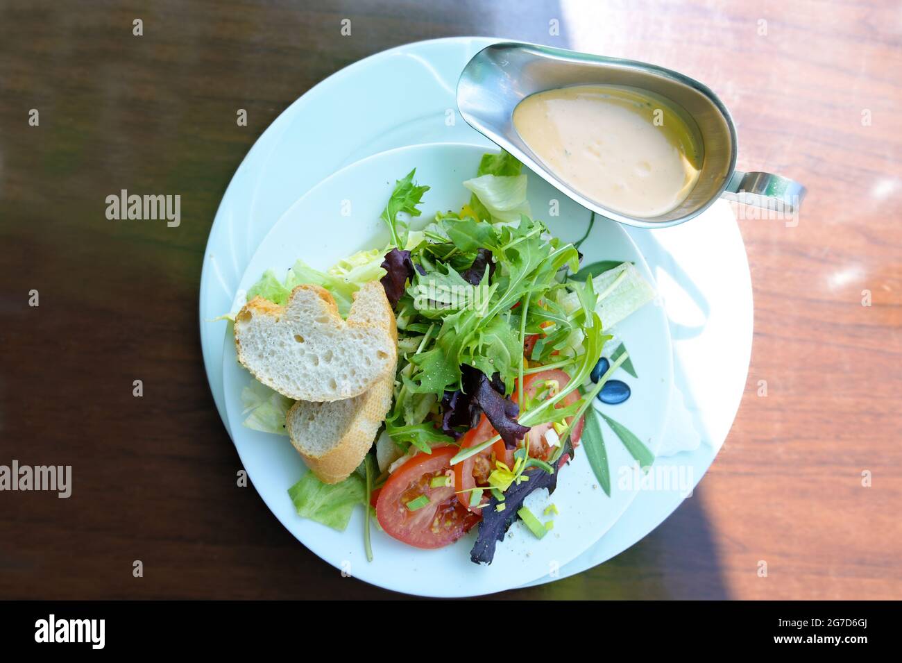 Insalata fresca di lattuga e pomodori con pane e condimento francese su un piatto bianco come un sano spuntino estivo, vista dall'alto, selezionato Foto Stock
