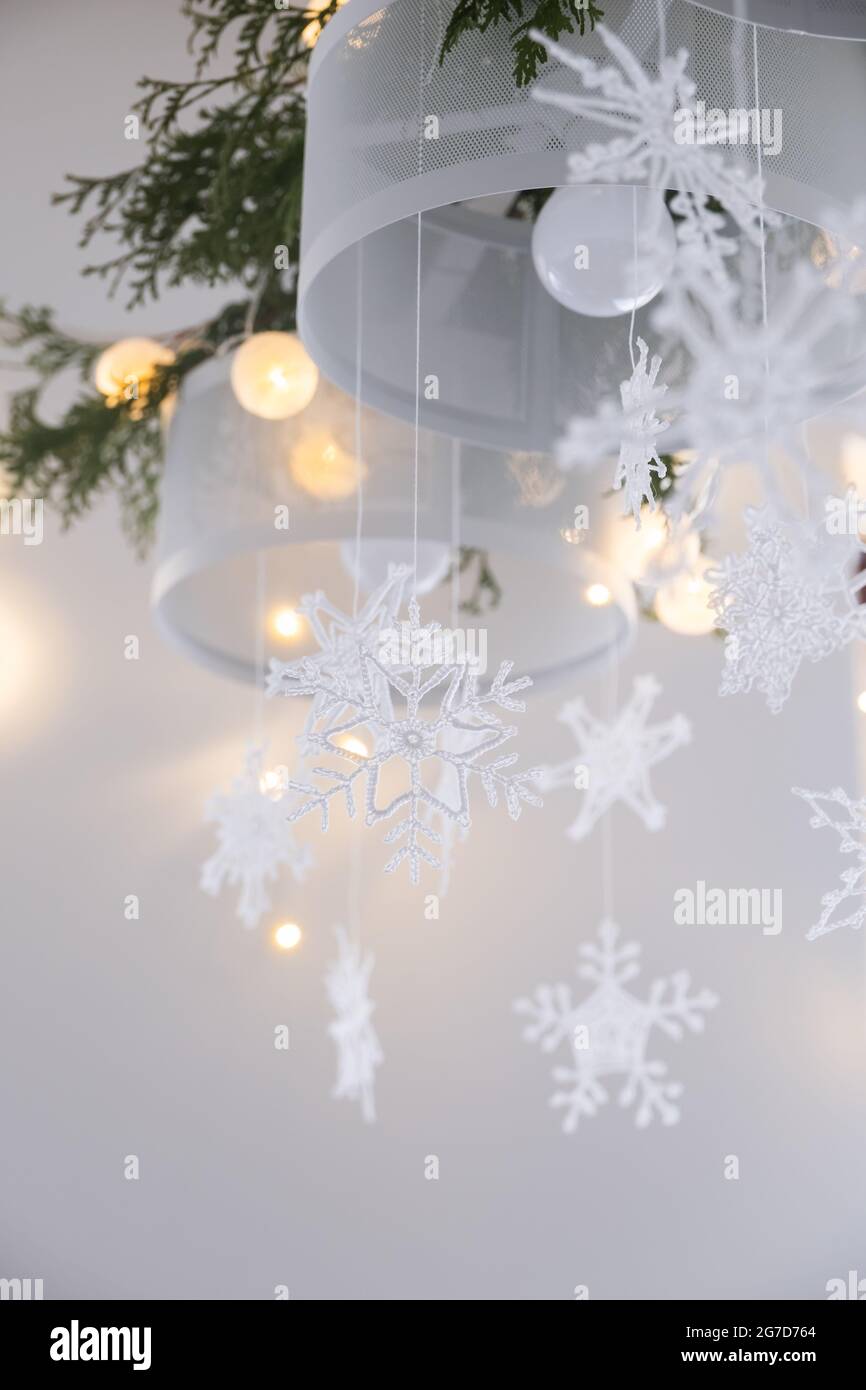Decorazione di interni di Natale. Fiocchi di neve lavorati a maglia bianca,  rami di abete e luci di natale su un lampadario Foto stock - Alamy