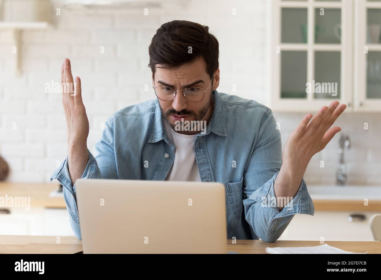 L'uomo irritato che fissava lo schermo del computer portatile ha problemi con il dispositivo Foto Stock
