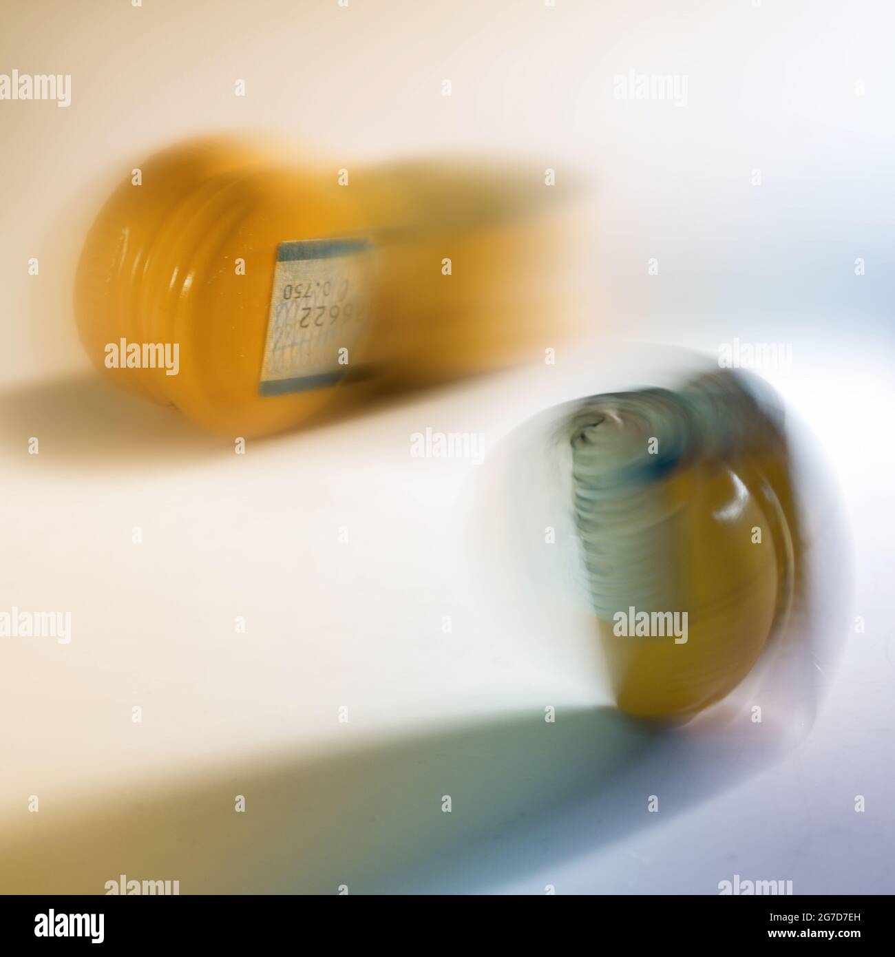 tappi a vite gialli in alluminio e plastica per bottiglie in movimento sfocano su sfondo chiaro, concetto astratto per una produzione sostenibile ed evitare Foto Stock