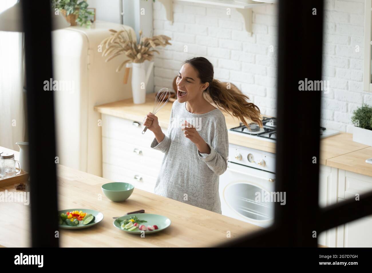 Giovane donna di razza mista che canta usando un frusta come un microfono Foto Stock
