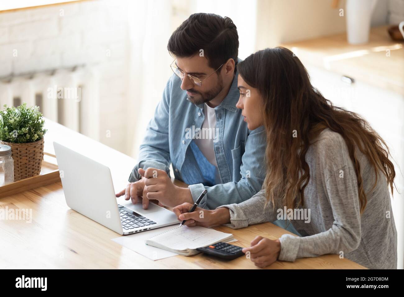 Coppia che guarda lo schermo del notebook che analizza le spese per la gestione del budget di famiglia Foto Stock