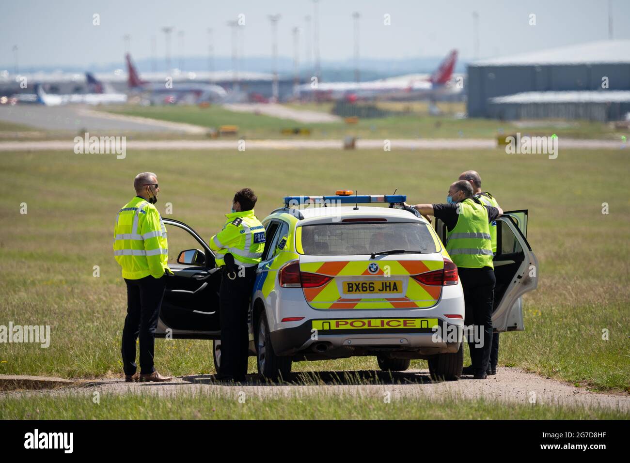 Gli agenti di polizia con la pattuglia marcata auto che sorvegliano la pista dell'aeroporto che mantengono i passeggeri dell'aeromobile al sicuro. In caso di allarme elevato, osservare le minacce. Foto Stock