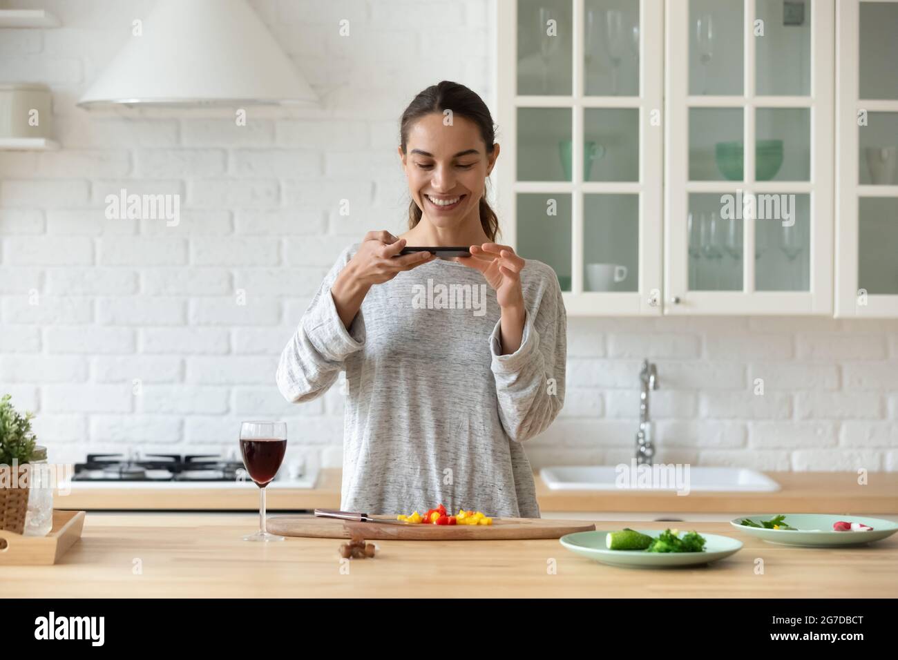 Donna tiene smartphone scatta foto di ingredienti di insalata di verdure a fette Foto Stock